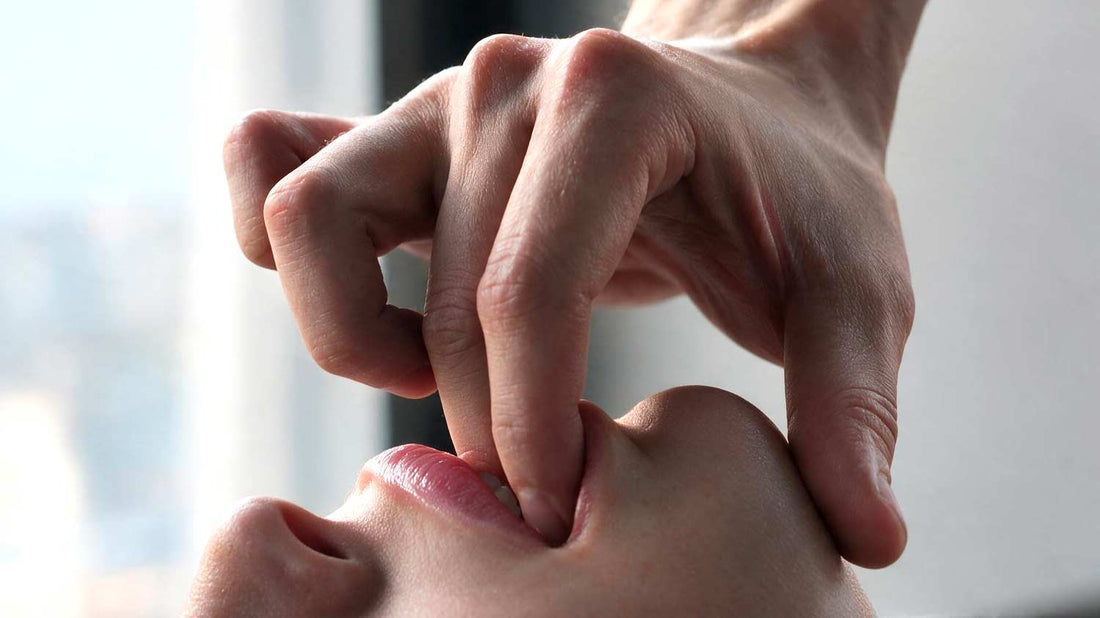 Close-up of a person lying down and using their fingers to stretch the inside of their mouth.