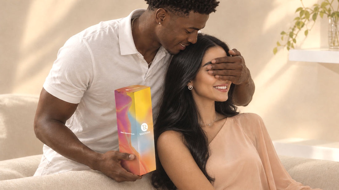 A smiling couple sits together on a sofa as the man playfully covers the woman’s eyes while holding a colorful TouchReal product box.