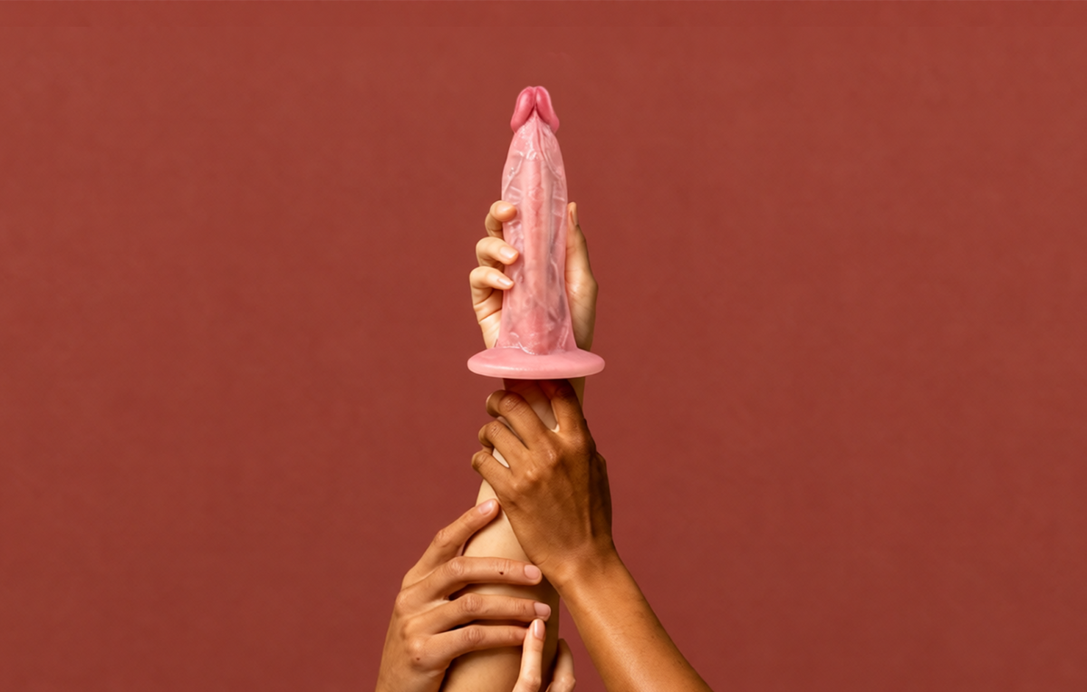 realistic dildo don held by two hands against a red background